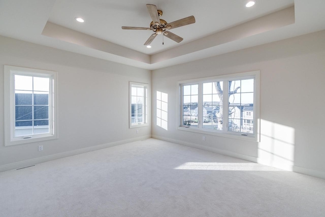 empty room featuring light colored carpet, ceiling fan, and a tray ceiling