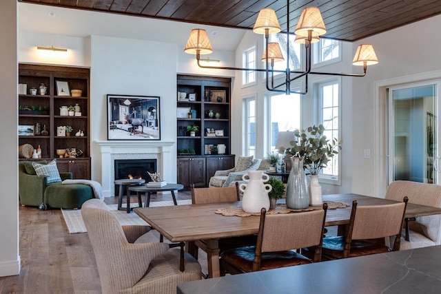 dining area with wood ceiling, hardwood / wood-style flooring, built in shelves, and a chandelier