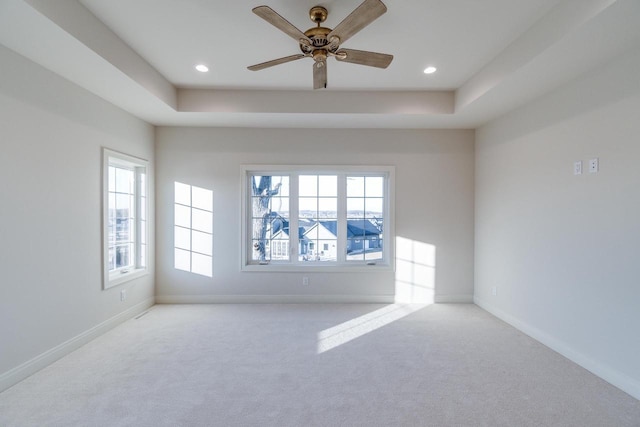 carpeted empty room featuring ceiling fan and a tray ceiling