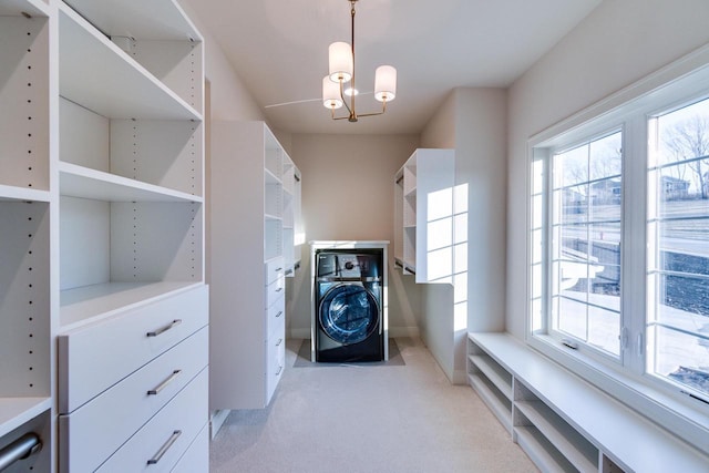 spacious closet with an inviting chandelier, washer / clothes dryer, and light colored carpet