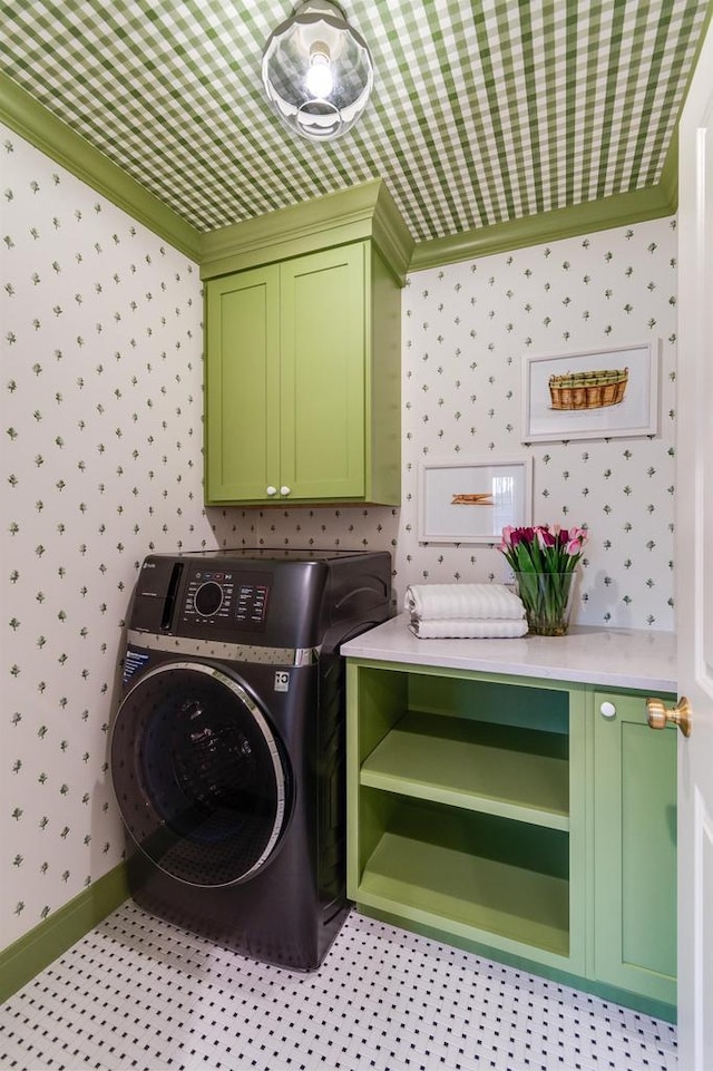 clothes washing area with crown molding, cabinets, and washer / dryer