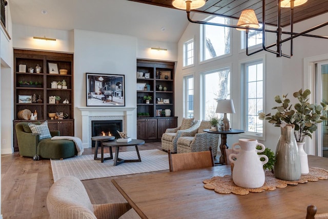 living room with hardwood / wood-style floors, a wealth of natural light, built in features, and high vaulted ceiling