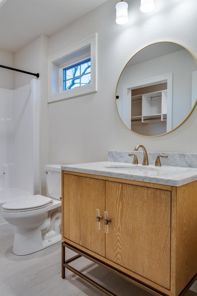 bathroom with hardwood / wood-style flooring, vanity, toilet, and a shower