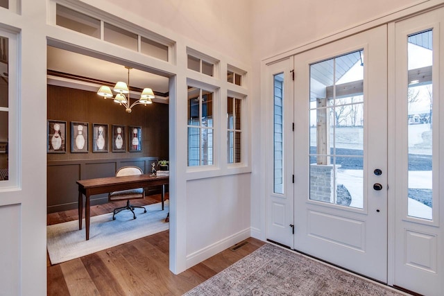 doorway featuring a notable chandelier, hardwood / wood-style flooring, and a healthy amount of sunlight