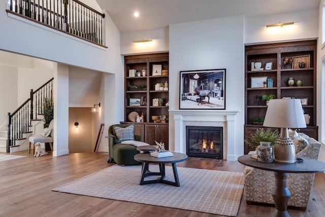 living area with hardwood / wood-style floors, built in shelves, and a high ceiling