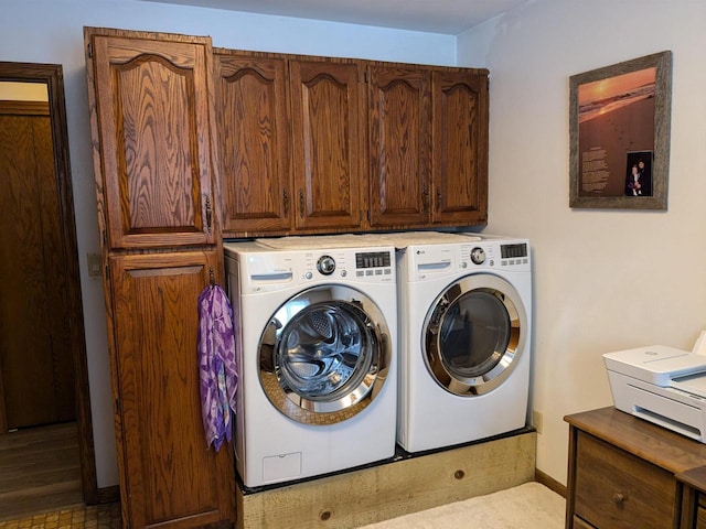 clothes washing area featuring cabinets and separate washer and dryer