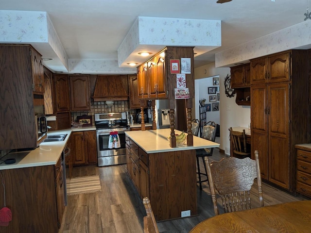 kitchen featuring a center island, backsplash, hardwood / wood-style flooring, appliances with stainless steel finishes, and custom range hood