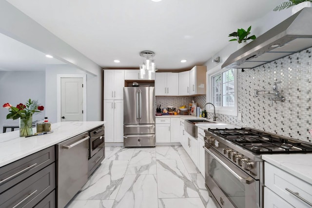 kitchen with white cabinetry, light stone counters, wall chimney range hood, and appliances with stainless steel finishes