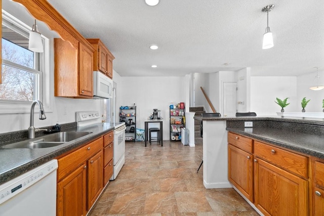 kitchen with pendant lighting, white appliances, a textured ceiling, and sink