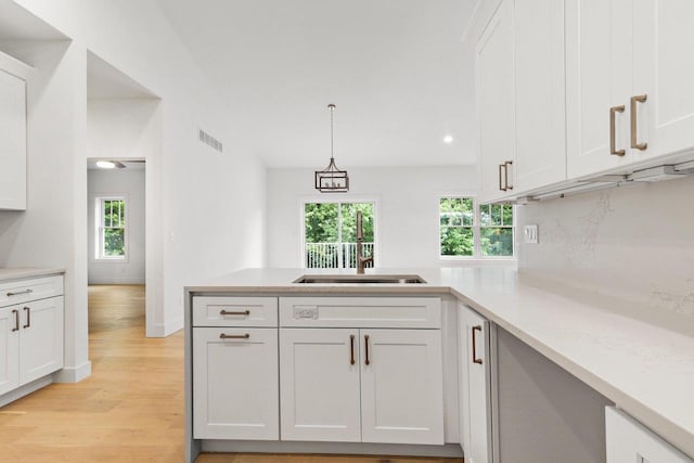 kitchen with white cabinets, a healthy amount of sunlight, and decorative light fixtures