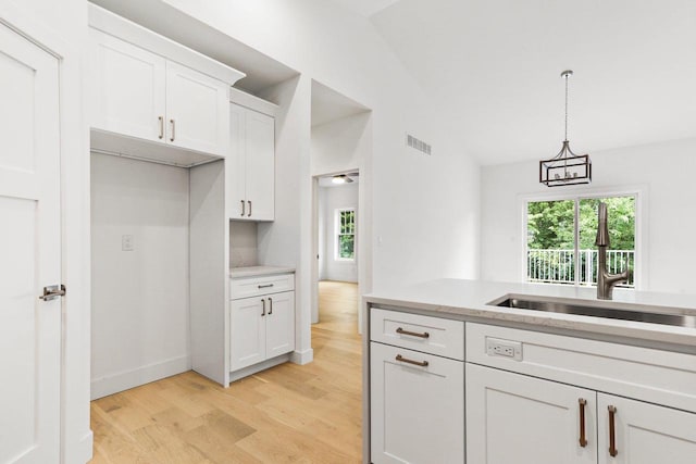 kitchen with sink, decorative light fixtures, white cabinets, light hardwood / wood-style floors, and lofted ceiling