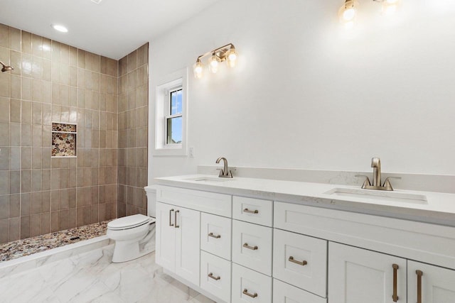 bathroom with tiled shower, vanity, and toilet