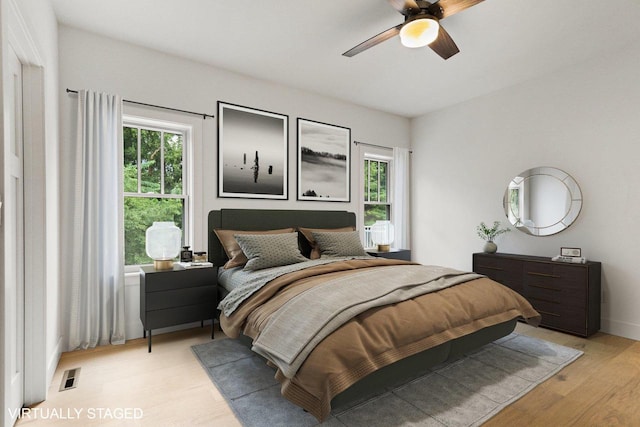 bedroom featuring ceiling fan, light hardwood / wood-style floors, and multiple windows