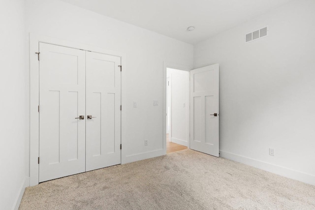 unfurnished bedroom with light colored carpet and a closet