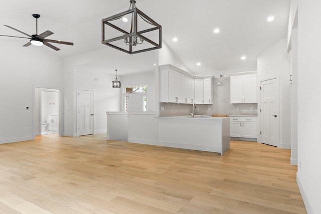 kitchen featuring decorative light fixtures, white cabinetry, high vaulted ceiling, and light hardwood / wood-style flooring