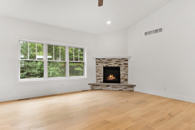 unfurnished living room featuring a fireplace, lofted ceiling, and light wood-type flooring