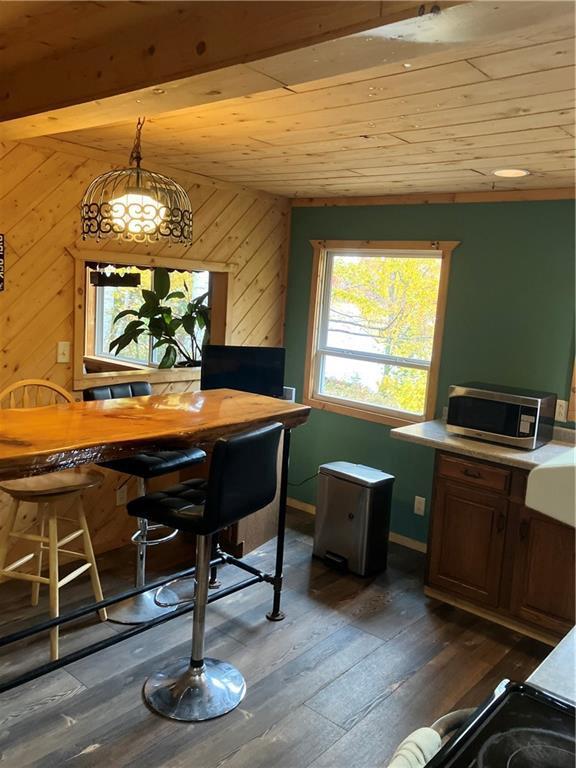 interior space featuring wood ceiling, wooden walls, dark hardwood / wood-style flooring, and hanging light fixtures