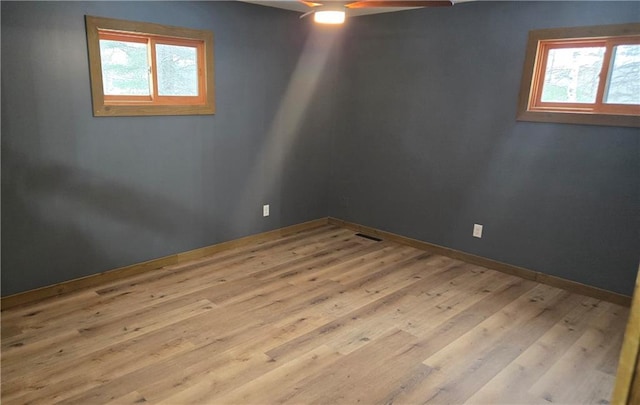 empty room featuring light wood-type flooring, ceiling fan, and a healthy amount of sunlight