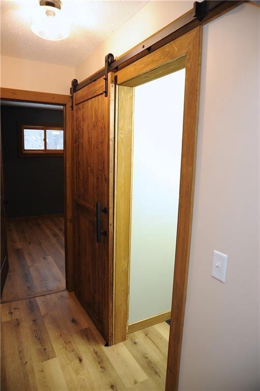 corridor with light hardwood / wood-style floors and a textured ceiling