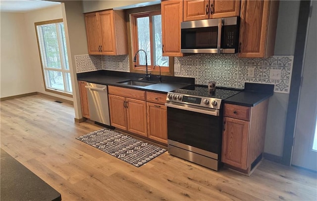 kitchen with decorative backsplash, light hardwood / wood-style floors, sink, and appliances with stainless steel finishes