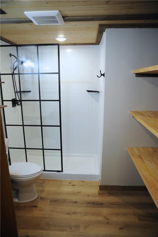 bathroom with a shower, wood-type flooring, and toilet