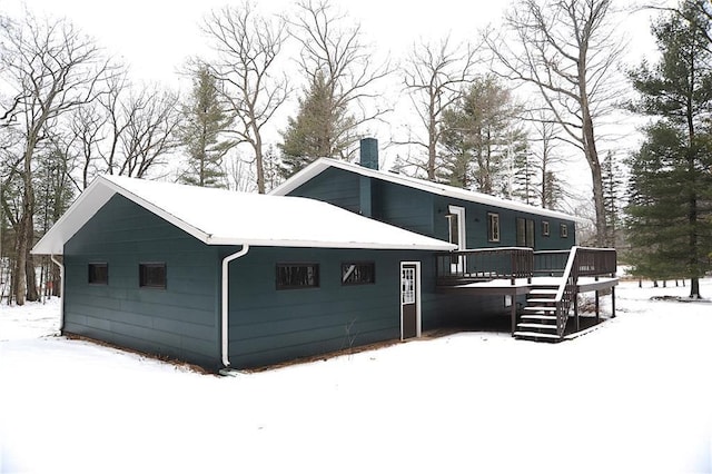 snow covered back of property with a deck