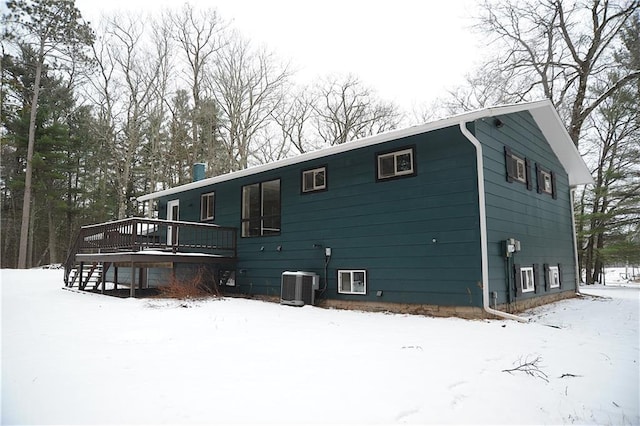 snow covered house featuring a wooden deck and central AC