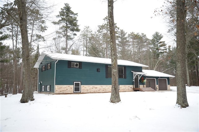 snow covered rear of property with a garage