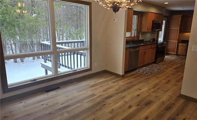 kitchen with sink, dark wood-type flooring, stainless steel dishwasher, a chandelier, and decorative backsplash