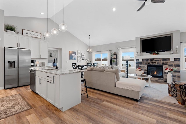 kitchen with white cabinets, sink, stainless steel appliances, and an island with sink