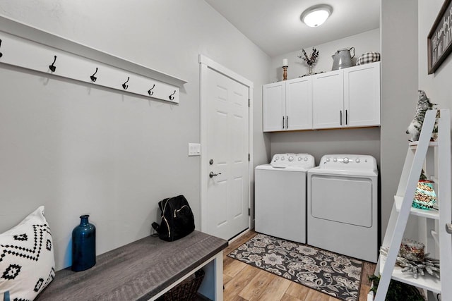 laundry area with independent washer and dryer, cabinets, and light hardwood / wood-style floors