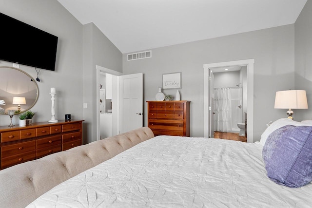 bedroom featuring ensuite bathroom and vaulted ceiling