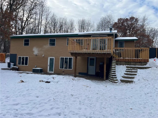 snow covered back of property featuring a deck and central AC unit