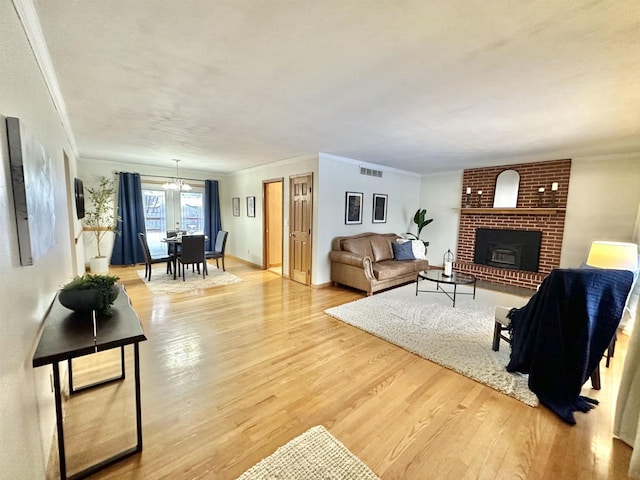 living room with a brick fireplace, light hardwood / wood-style flooring, and ornamental molding