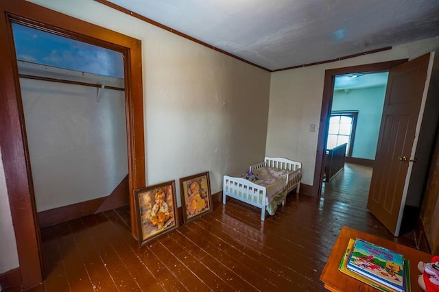 bedroom with ornamental molding, dark wood-type flooring, and a closet