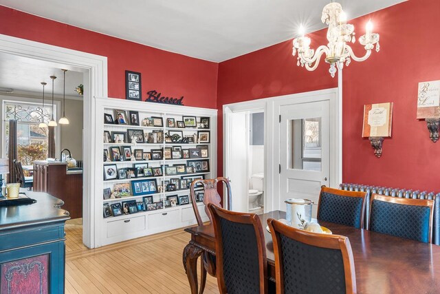dining area with hardwood / wood-style flooring, built in shelves, and an inviting chandelier