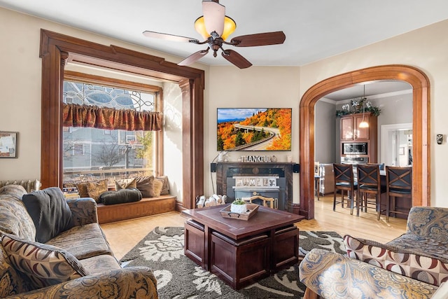 living room featuring ceiling fan with notable chandelier, crown molding, and a fireplace