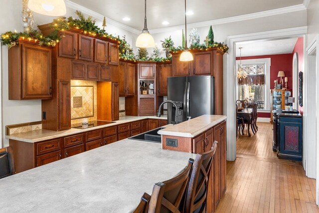 kitchen with pendant lighting, sink, stainless steel refrigerator with ice dispenser, an island with sink, and a breakfast bar area