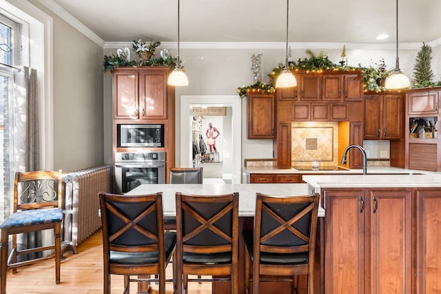 kitchen featuring radiator, stainless steel appliances, hanging light fixtures, and crown molding