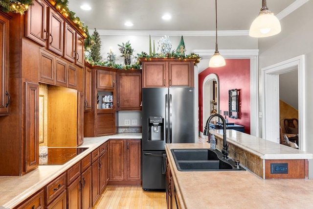 kitchen featuring pendant lighting, black electric stovetop, sink, stainless steel refrigerator with ice dispenser, and ornamental molding