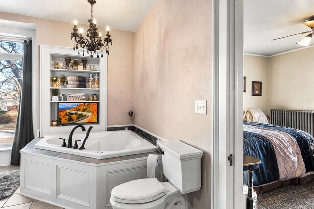 bathroom with tile patterned flooring, ceiling fan with notable chandelier, toilet, and a bathing tub