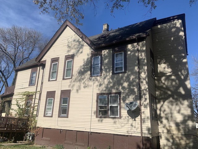 view of side of home with a wooden deck and a chimney