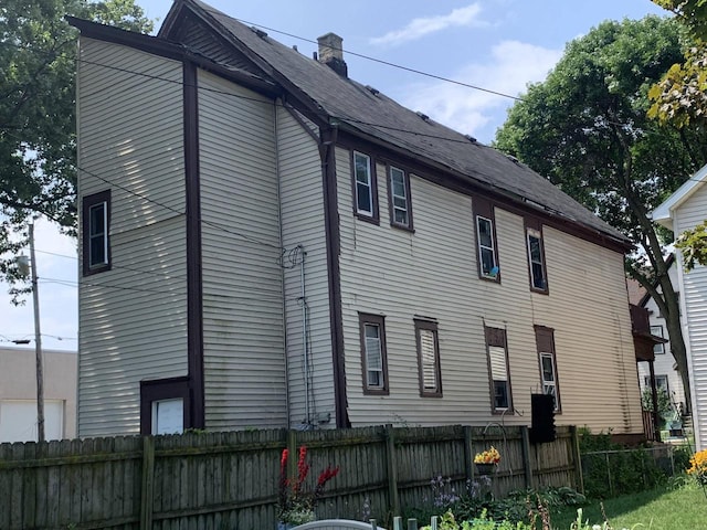 view of side of home with fence and a chimney