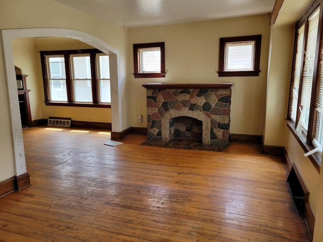 unfurnished living room with wood-type flooring, baseboards, and a fireplace