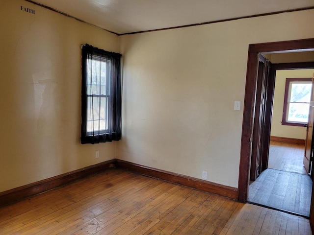 spare room with crown molding, baseboards, visible vents, and hardwood / wood-style floors