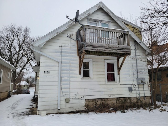 snow covered back of property with a balcony