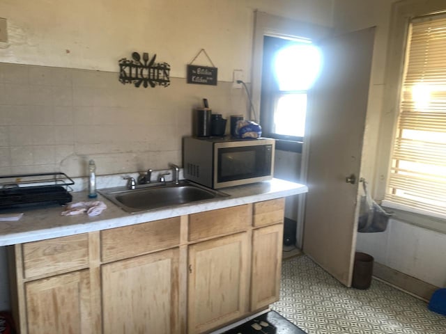 kitchen with light brown cabinetry, decorative backsplash, and sink