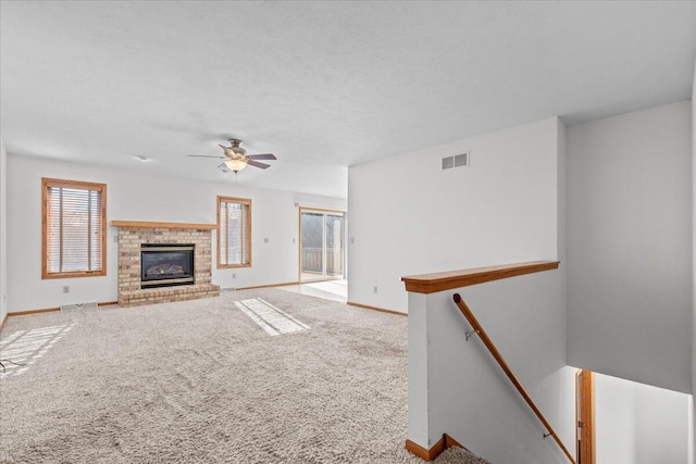 unfurnished living room with carpet floors, ceiling fan, a healthy amount of sunlight, and a fireplace