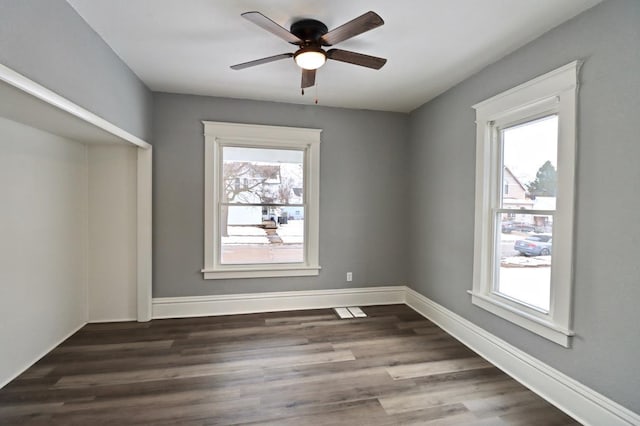 spare room with plenty of natural light, ceiling fan, and dark wood-type flooring