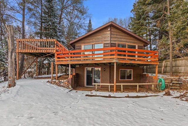 snow covered back of property featuring a deck